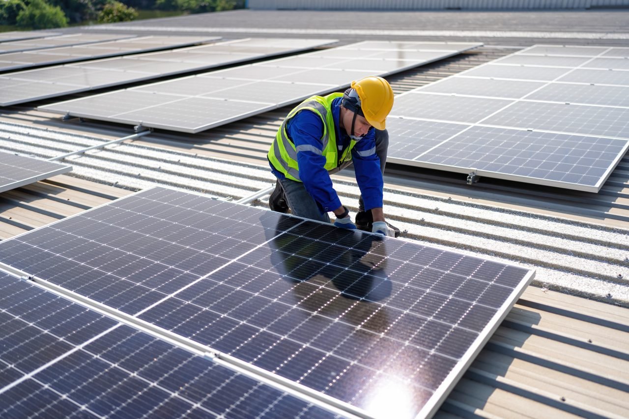 engineer-on-rooftop-kneeling-next-to-solar-panels-photo-voltaic-with-tool-in-hand-for-installation.jpg